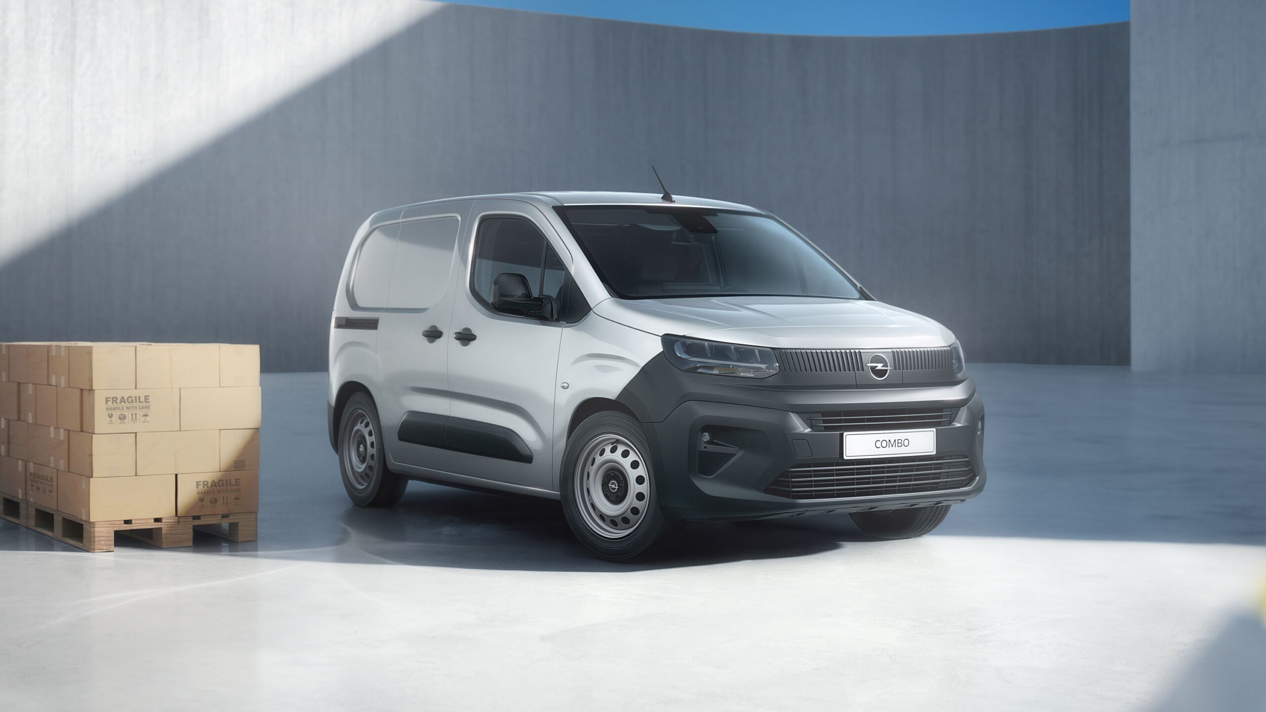 Opel Combo Start cinzento junto a caixas de carga